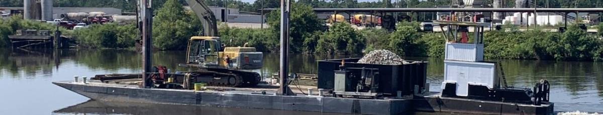 Krause Marine Construction barge with an excavator, a load of stone and a push boat