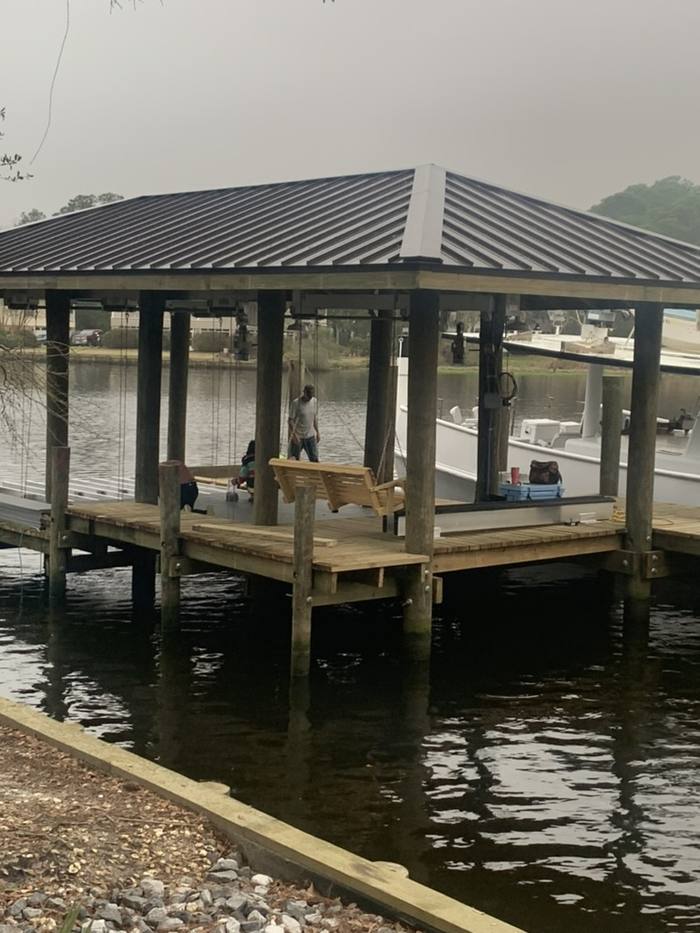 Covered boathouse with a dark metal roof at the end of the pier