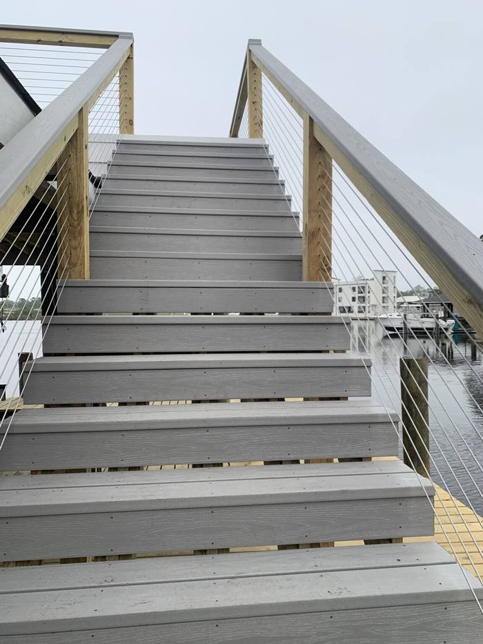 Composite stairs with stainless cable rails up to a deck over the boat slip