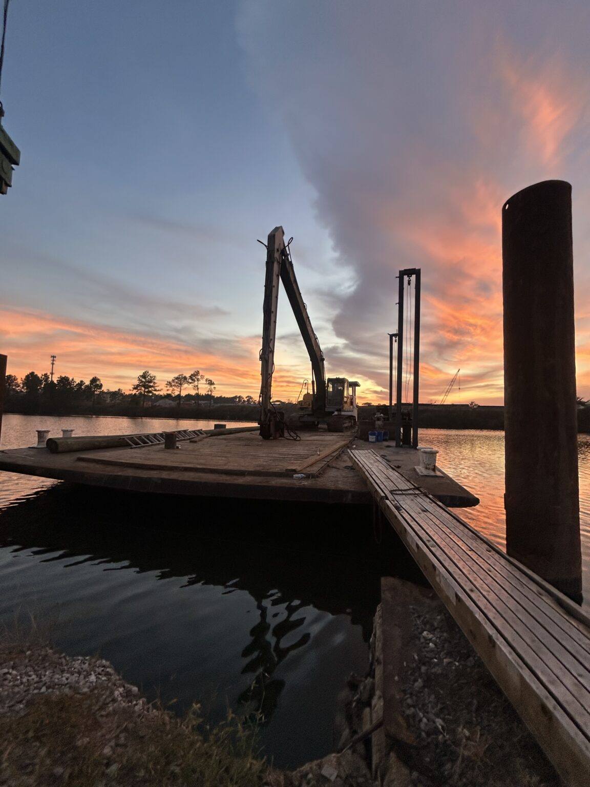 Krause Marine Construction's barge and excavator at dusk on the Pass Christian steel wall job