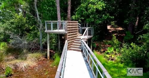 Raised walkway with metal rails and an overlook through the woods on the Fort Bayou trail