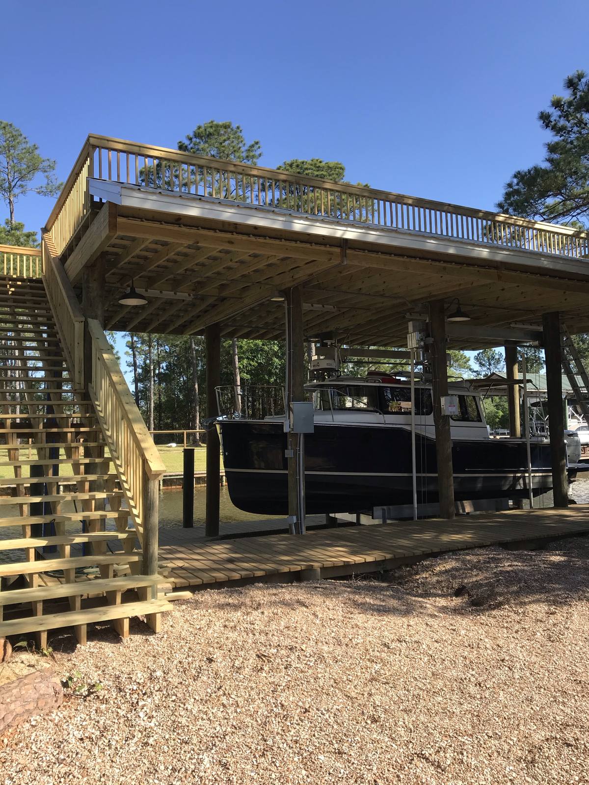 Boathouse with an observation deck and stairs, a Ranger Tug on the lift below