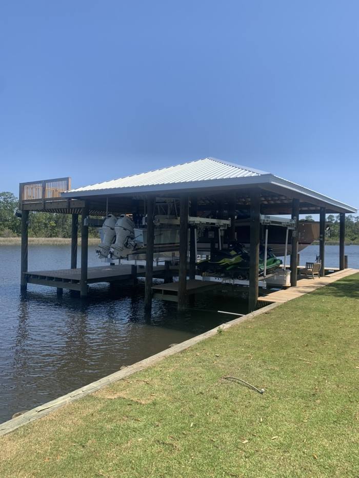 Large boathouse with a white metal roof and a railed sun deck on the Tchoutacabouffa River