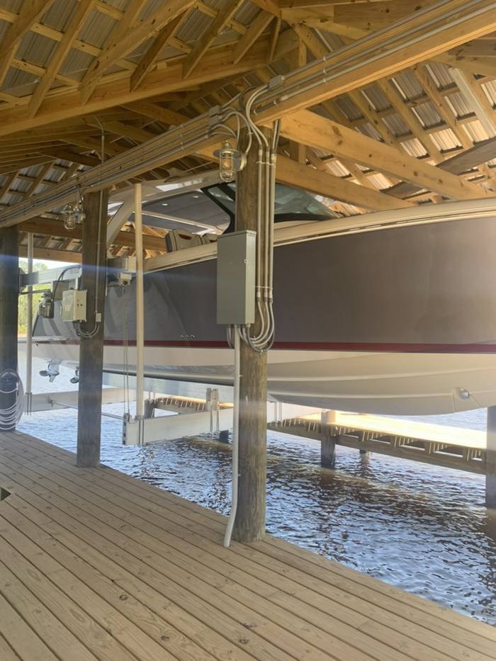 Boat raised on a lift under the boathouse roof
