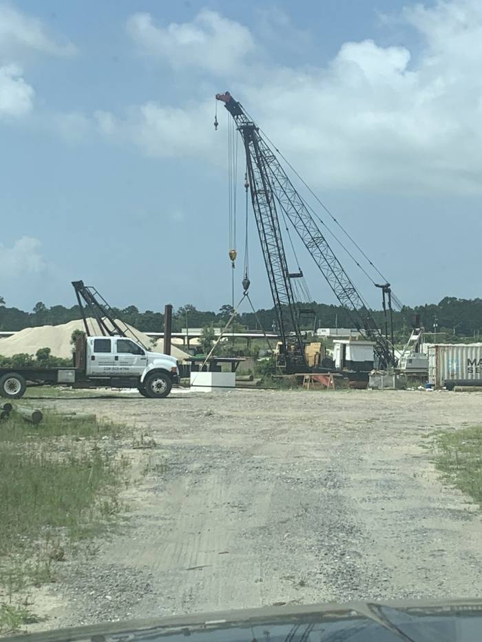 Lattice-boom crane and a work truck on a gravel lot